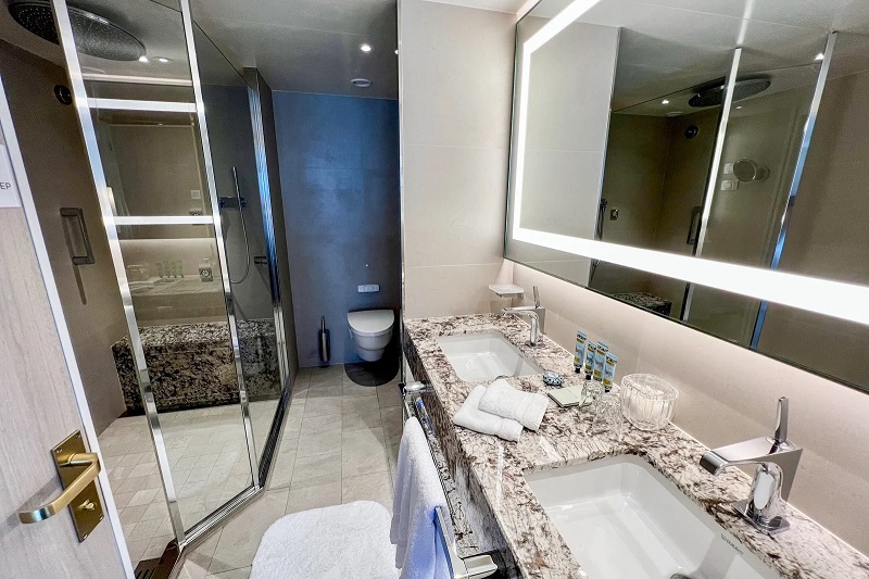 Các phòng tắm của Sapphire Verandah Suite có bàn trang điểm bằng đá cẩm thạch với bồn rửa đôi và góc tắm vòi sen mở lớn